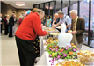 People walk down buffet tables plating food.