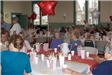 Senior citizens sit at tables together decorated with star balloons and popcorn buckets.