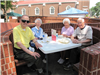 Two men and two woman sit together in brick booth.