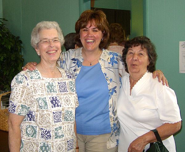 Three women smile together.