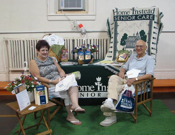 Man and woman sit at Home Instead Senior Care booth.