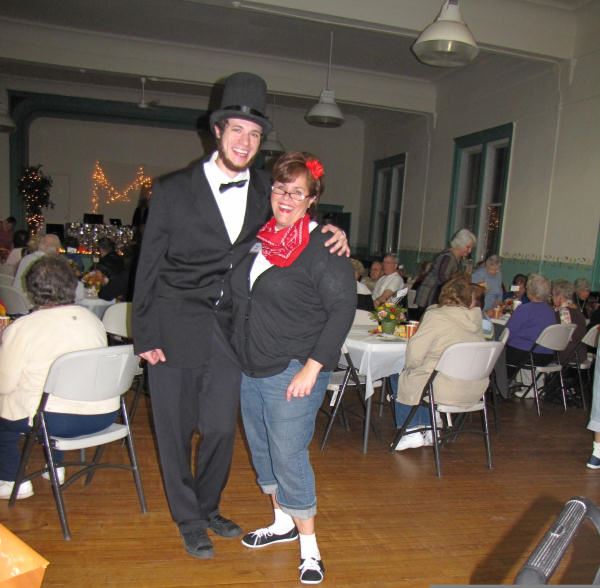 Man dressed as Abraham Lincoln smiles next to woman with red handkerchief around her neck.