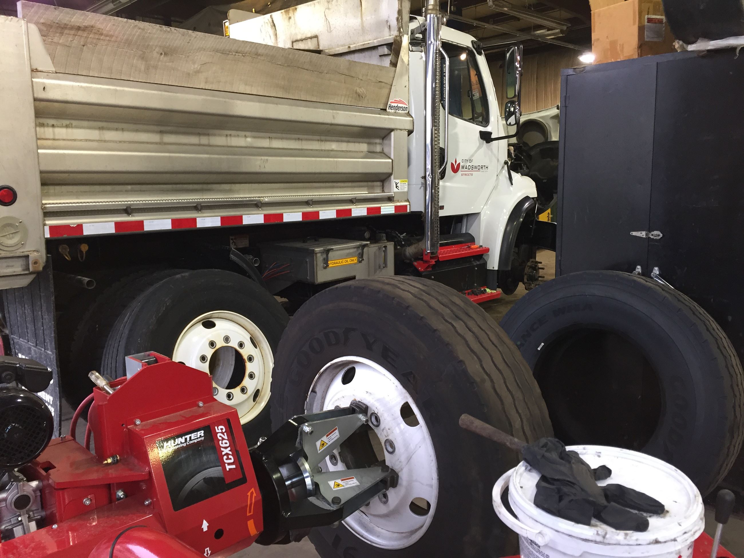 A dump truck in a maintenance garage surrounded by tires.